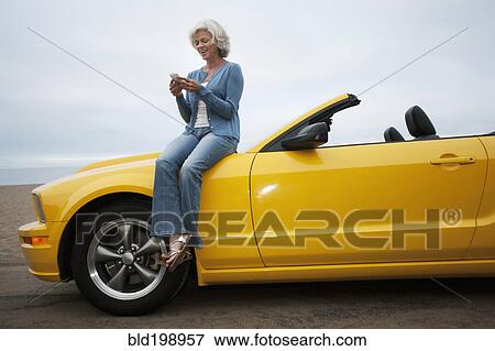 Stock Photo - Caucasian woman sitting on convertible at beach. Fotosearch
