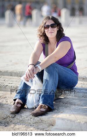 Stock Image - Caucasian woman sitting on steps. Fotosearch