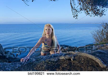 Stock Image - Caucasian woman standing near ocean. Fotosearch