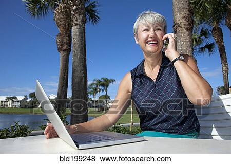 Caucasian woman talking on telephone and using laptop View Large Photo Image Stock Photo - Caucasian woman talking on telephone and using laptop. Fotosearch