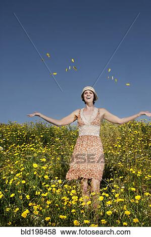Stock Photo - Caucasian woman throwing wildflowers in field. Fotosearch