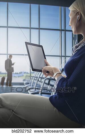 Stock Image - Caucasian woman using digital tablet in airport. Fotosearch