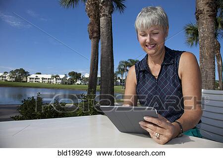 Stock Photo - Caucasian woman using digital tablet outdoors. Fotosearch