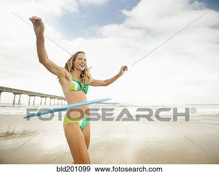 Stock Photo - Caucasian woman using plastic hoop on beach. Fotosearch