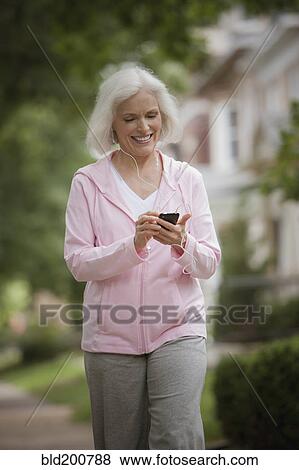 Caucasian woman walking and listening to mp3 player View Large Photo Image Stock Photo - Caucasian woman walking and listening to mp3 player. Fotosearch