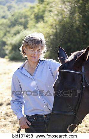 Stock Photo - Caucasian woman watching horse. Fotosearch