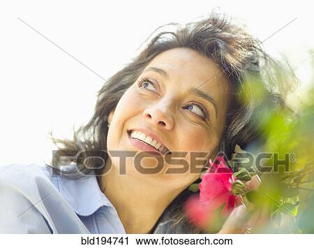 Stock Image - Caucasian woman with flower outdoors. Fotosearch