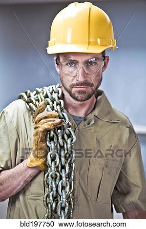 Stock Image - Caucasian worker in hard-hat holding chains. Fotosearch