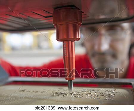 Stock Photo - Caucasian worker using branding machine in factory. Fotosearch