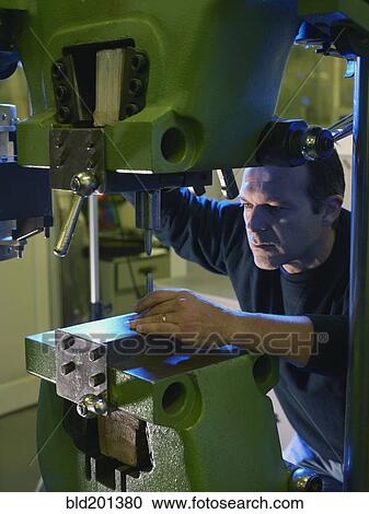 Stock Image - Caucasian worker using industrial drill. Fotosearch