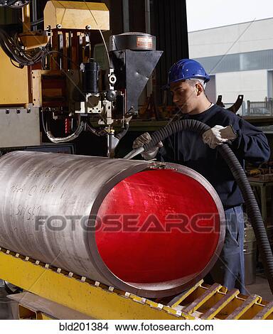 Picture - Caucasian worker working on steel pipe in factory. Fotosearch