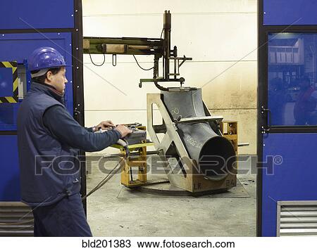 Stock Image - Caucasian worker working on steel pipe in factory. Fotosearch