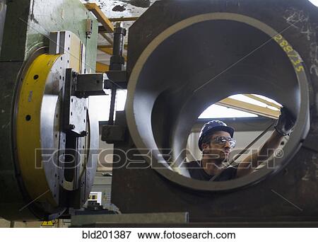Stock Photo - Caucasian worker working on steel pipe in factory. Fotosearch