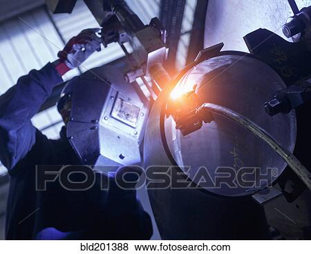 Stock Photo - Caucasian worker working on steel pipe in factory. Fotosearch