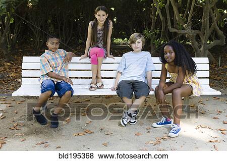 Children sitting on park bench View Large Photo Image Stock Photo - Children sitting on park bench. Fotosearch
