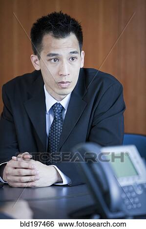 Stock Photograph - Chinese businessman sitting in conference room. Fotosearch