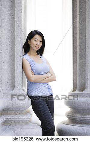 Stock Photograph - Chinese businesswoman leaning against stone pillar. Fotosearch