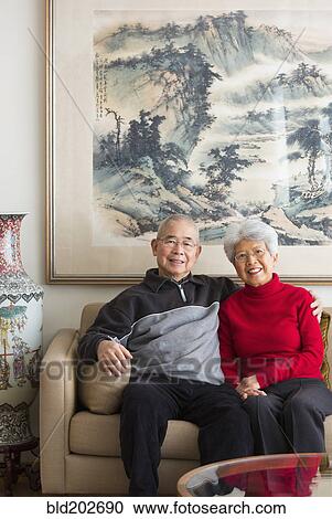 Stock Image - Chinese couple sitting on sofa. Fotosearch