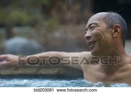 Stock Image - Chinese man relaxing in hot tub. Fotosearch