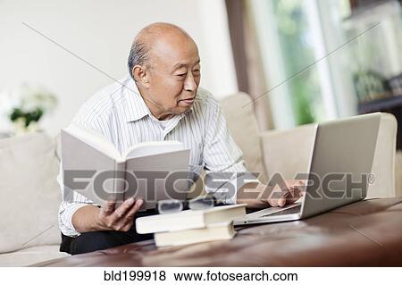 Chinese man with book and laptop View Large Photo Image Stock Photo - Chinese man with book and laptop. Fotosearch
