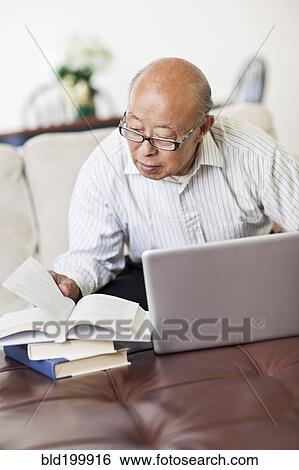 Chinese man with book and laptop View Large Photo Image Stock Photograph - Chinese man with book and laptop. Fotosearch
