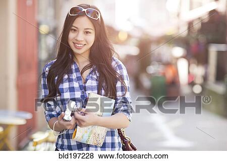 Stock Photo - Chinese woman holding map and digital camera. Fotosearch