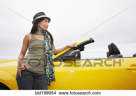 Picture - Chinese woman leaning on convertible. Fotosearch