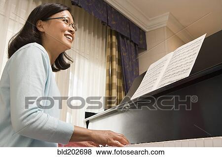 Stock Photo - Chinese woman playing piano. Fotosearch