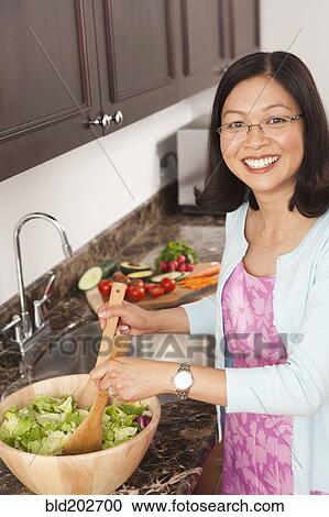 Chinese woman tossing salad in kitchen View Large Photo Image Stock Image - Chinese woman tossing salad in kitchen. Fotosearch