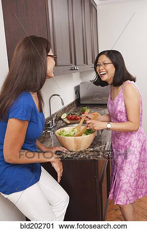 Stock Image - Chinese women talking in kitchen. Fotosearch