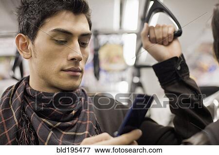 Close up of mixed race man text messaging with cell phone on subway View Large Photo Image Stock Photo - Close up of mixed race man text messaging with cell phone on subway. Fotosearch