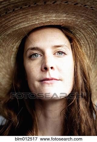 Stock Photo - Close up of serious woman wearing straw hat. Fotosearch