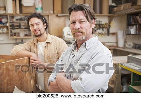 Stock Photograph - Co-workers woodworking in workshop. Fotosearch