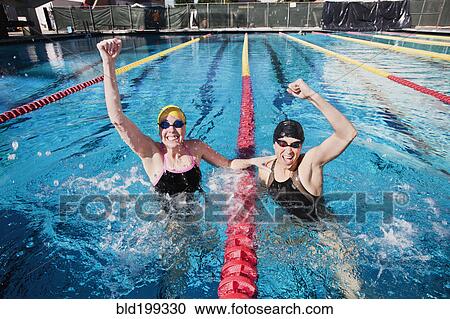 Stock Image - Competitive swimmers cheering in swimming pool. Fotosearch