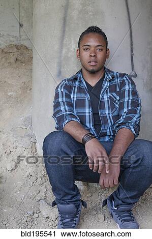 Confident Black teenage boy crouching View Large Photo Image Stock Image - Confident Black teenage boy crouching. Fotosearch
