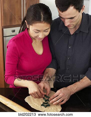 Stock Image - Couple baking together in kitchen. Fotosearch