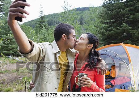 Stock Photography - Couple camping, kissing and taking self-portrait. Fotosearch