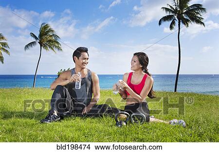 Picture - Couple drinking water after exercise at waterfront. Fotosearch
