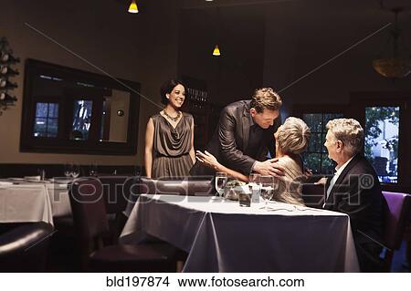 Picture - Couple greeting friends in restaurant. Fotosearch