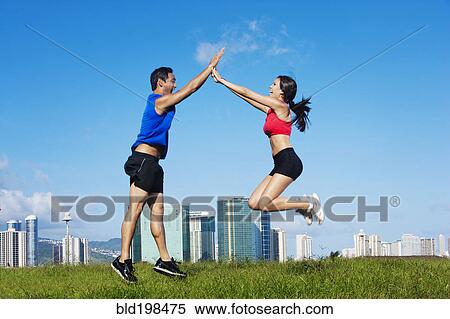 Stock Photography - Couple high-fiving in field. Fotosearch