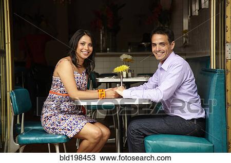 Stock Image - Couple holding hands in restaurant. Fotosearch