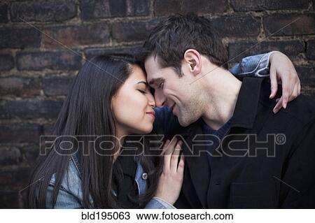Stock Image - Couple hugging against wall. Fotosearch