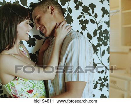 Stock Image - Couple hugging in front of wallpaper. Fotosearch