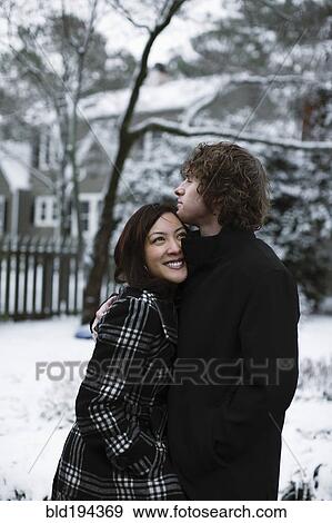 Stock Photo - Couple hugging outdoors in snow. Fotosearch