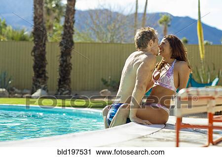 Stock Image - Couple kissing at poolside. Fotosearch