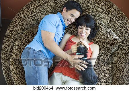 Picture - Couple laying together petting dog. Fotosearch