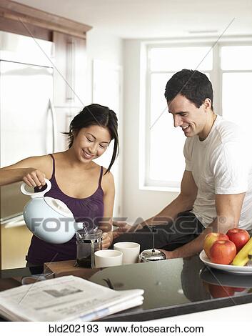 Stock Image - Couple preparing coffee in kitchen. Fotosearch