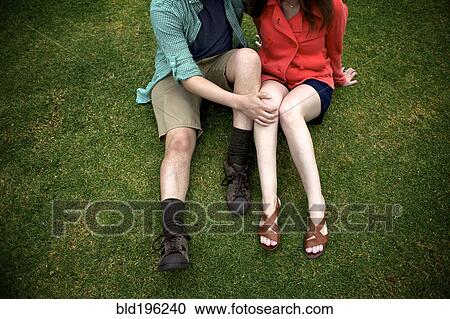Stock Image - Couple sitting on grass together. Fotosearch