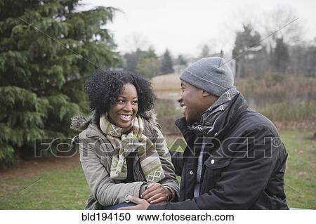 Stock Image - Couple sitting together in park. Fotosearch