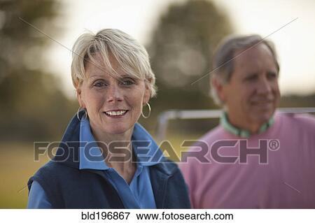 Couple standing on golf course View Large Photo Image Stock Photo - Couple standing on golf course. Fotosearch